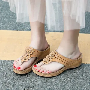 Détail de sandales compensées kaki avec fleurs 3D et perforations latérales au laser