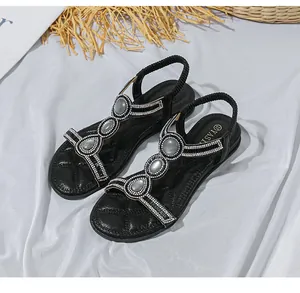 Detail von schwarzen Bohemian-Sandalen mit funkelnden Strasssteinen und T-Riemen