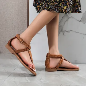 Detail of snake skin texture and metal buckle on women's tan T-strap flat sandals
