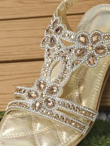 Detailed macro view of gold flat sandals featuring champagne gems and diamond accents