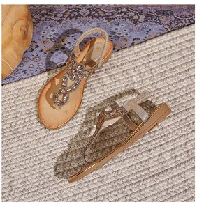 Détail de sandales plates bohèmes dorées avec des strass complexes et des broderies