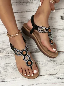 Detail of bohemian black sandals with sparkling rhinestones and floral pattern for women