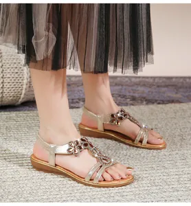 Detailansicht der champagnergoldenen Sandalen mit floralem Edelsteinmuster und Strasssteinen