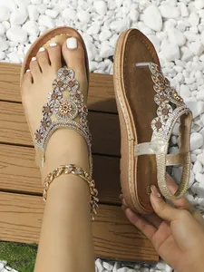 Detail von Boho-Flachsandalen mit funkelnden Strasssteinen und Sonnenblumen-Metallverzierung