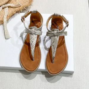 Flat gladiator sandal detail featuring snake print strap, bow design and gold buckle