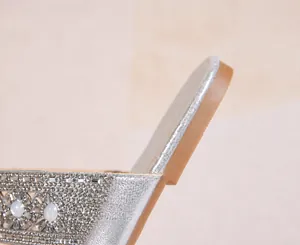 Détail de strass étincelants sur des sandales argentées avec un talon plat de 1 cm