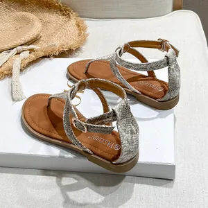 Detail of snake skin pattern straps and gold buckle on women's flat bohemian sandals