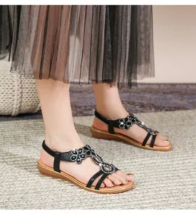 Detail von böhmischen flachen Sandalen mit glitzernden Strass-Blumen auf dem T-Riemen