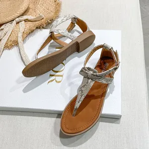 Close-up of beige snake print flat thong sandals with ankle strap and bow detail