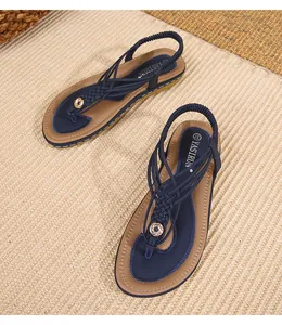 Détail de sandales plates bohèmes bleu marine avec brides tressées et anneau doré