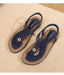 Détail de sandales bohèmes avec brides tressées bleu marine et ornements métalliques