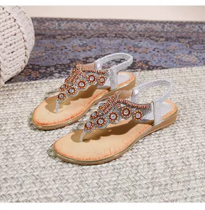Λεπτομερής όψη από boho σανδάλια με πορτοκαλί χάντρες και χρυσές πούλιες στο πάνω μέρος