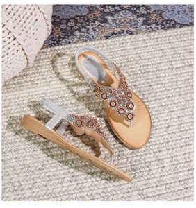 Λεπτομέρεια από φλατ σανδάλια boho με πολύχρωμες χάντρες και σχέδιο T-strap με στρας