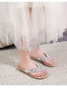 Detailopname van zilveren lederen teenslippers met sprankelende strass-steentjes in bladvorm