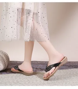 Detail van boho-sandalen met bladvormige strassteentjes op zwarte bandjes en beige plateauzool