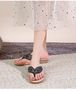 Detail van bohemian platte sandalen met fonkelende zwarte en gouden strasstenen op bandjes