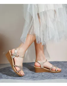 Details von Strass-Riemchen und Keilabsatz auf eleganten Damensandalen in Champagnergold