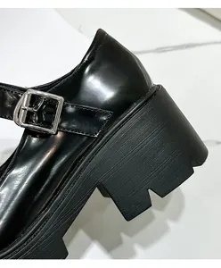 Detailopname van zwarte lakleer Mary Jane schoen met blokhak en zilveren gesp detail