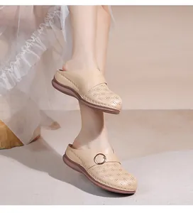 Détail de mules beiges ajourées avec boucle en métal et semelle plateforme sur robe