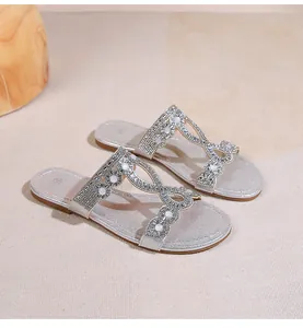 Détail de sandales plates bohèmes argentées avec strass étincelants et perles blanches