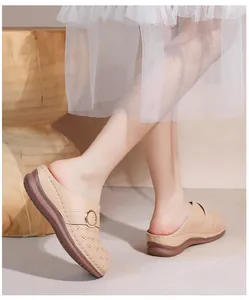 Détail de mules en cuir ajouré beige avec boucle en métal et semelle épaisse sur modèle