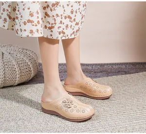 Detailed view of beige hollow-out wedge mules with floral accents on a patterned carpet