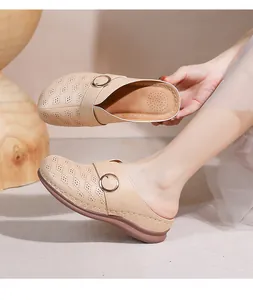 Détail de la tige en cuir beige ajouré avec boucle dorée sur mule femme à semelle compensée