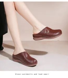 Détail de mules en cuir marron foncé avec motifs ajourés au laser et boucle latérale