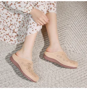 Detail view of beige hollow-out mules featuring laser-cut floral patterns on a woven carpet