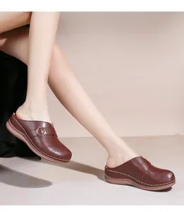 Détails de mules en cuir marron foncé avec motifs ajourés et boucle dorée ronde