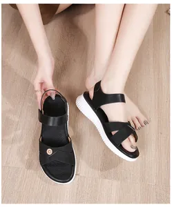 Detail of bohemian black sandals with crossed straps and gold metallic accents