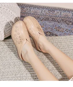 Close-up of beige hollow-out mule shoes with floral details and soft rubber soles