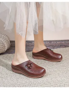 Detail of dark brown hollow out mule shoes with floral decor and stitched thick soles