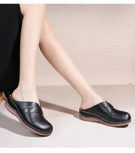 Détail d'une mule en cuir noir ajouré avec boucle métallique et surpiqûres blanches