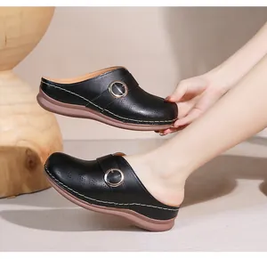 Détail de sabots noirs avec surpiqûres blanches et boucle en métal doré décorative