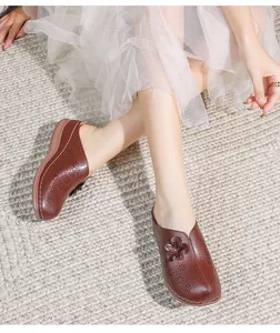 Close-up of hollowed-out brown mule sandals with 3D flower details and soft thick soles