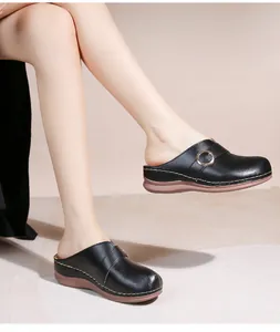 Détail de mule noire ajourée avec semelle épaisse, boucle métal et couture blanche