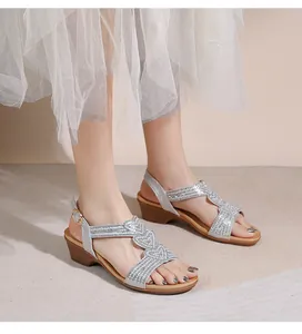 Nahaufnahme glitzernder Strass-Sandalen mit Herz-Design und Keilabsatz am Fuß