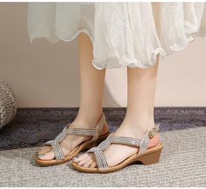 Détail de sandales compensées bohèmes avec brides croisées strassées et boucle en métal