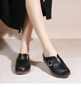Détails des mules en cuir noir avec perforations laser et boucle anneau doré chic