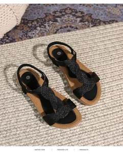 Λεπτομέρεια από μαύρα πλεκτά φλατ σανδάλια με καφέ πάτο και ελαστικό λουράκι φτέρνας