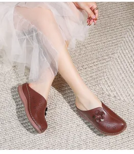 Close-up of brown leather hollow-out clogs with 3D flower detail and thick soft soles