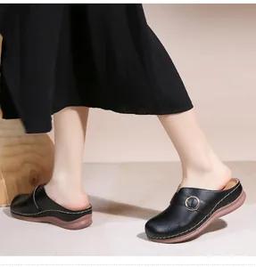 Détail de mules noires ajourées avec boucle dorée et semelles épaisses en gomme