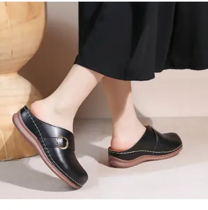 Détail de mules en cuir noir avec perforations et semelle souple cousue main