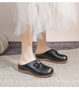 Close-up of black hollow-out mule shoes with floral cutouts and 3D leather flower detail