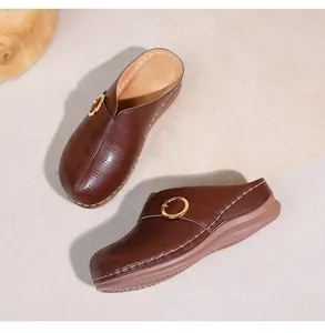 Détail de mule marron avec motifs ajourés, boucle dorée et semelle compensée épaisse