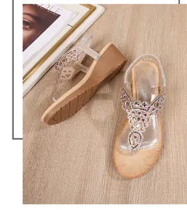 Close-up of champagne wedge sandals with sparkling rhinestones on wood background