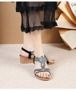 Detail of bohemian black wedge sandals featuring sparkling rhinestone floral T-strap design