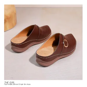 Détail de mule en cuir marron avec perforations laser et boucle en métal doré