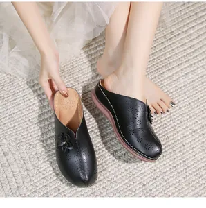 Close-up of black leather mule with floral hollow-out patterns and 3D petal accents